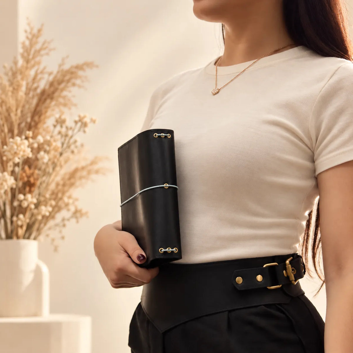 Woman showcasing a handmade leather journal cover while holding it securely with both hands.