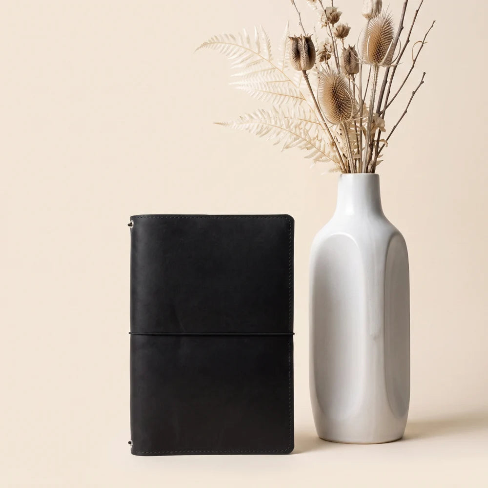 Minimalist leather notebook holder designed to accommodate three refillable inserts.