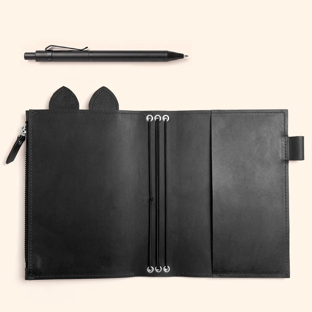 Handmade leather journal organizer with large zipper pocket, pen holder, decorative ears, and elastic closures.