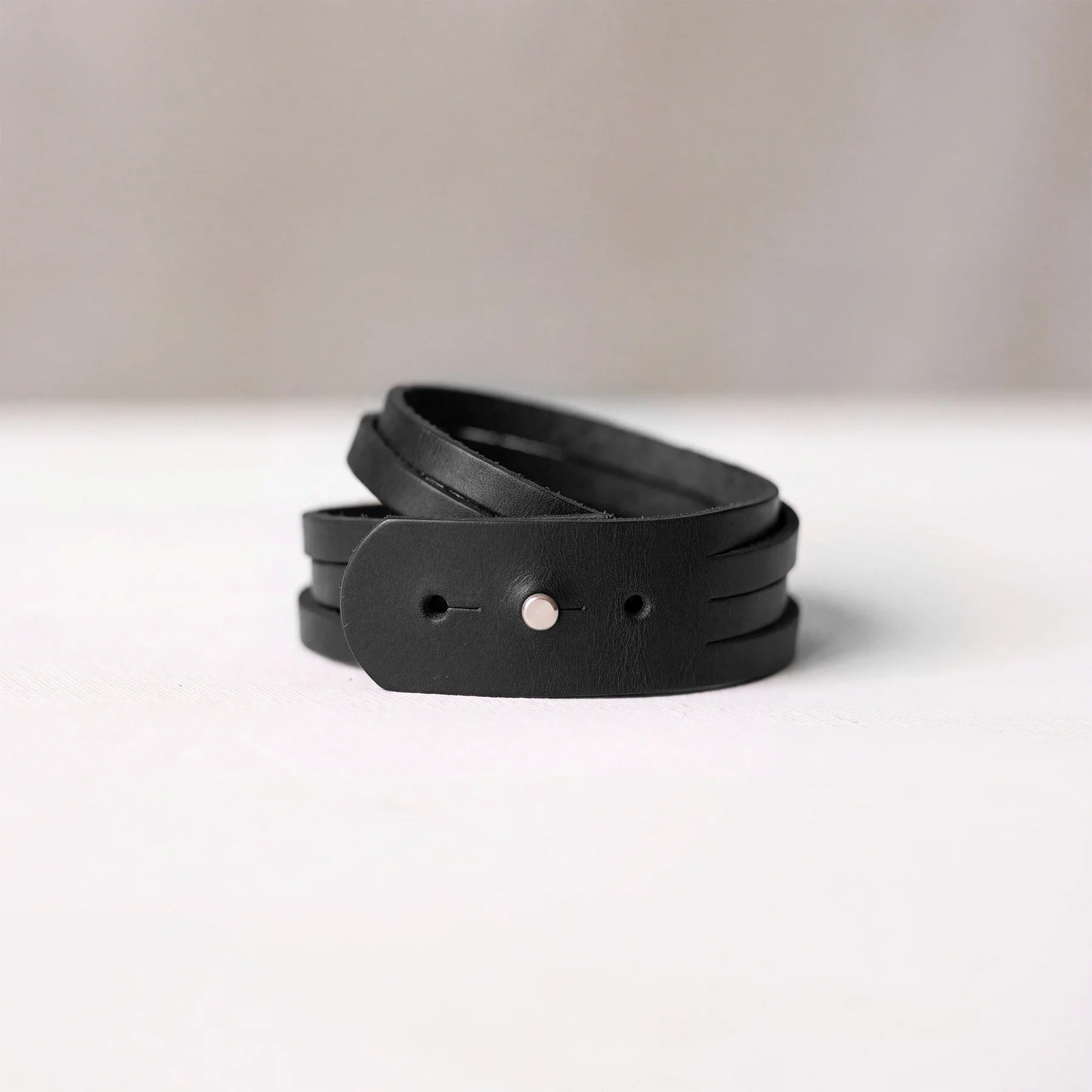 Black genuine leather bracelet featuring durable snap button fastening for comfortable daily wear.
