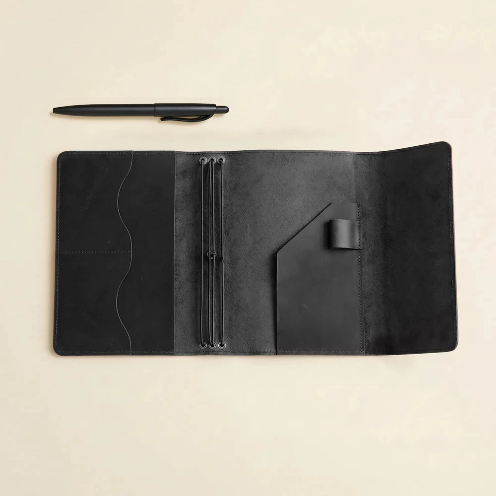 Stylish leather journal holder featuring elastic notebook bands and functional storage compartments inside.