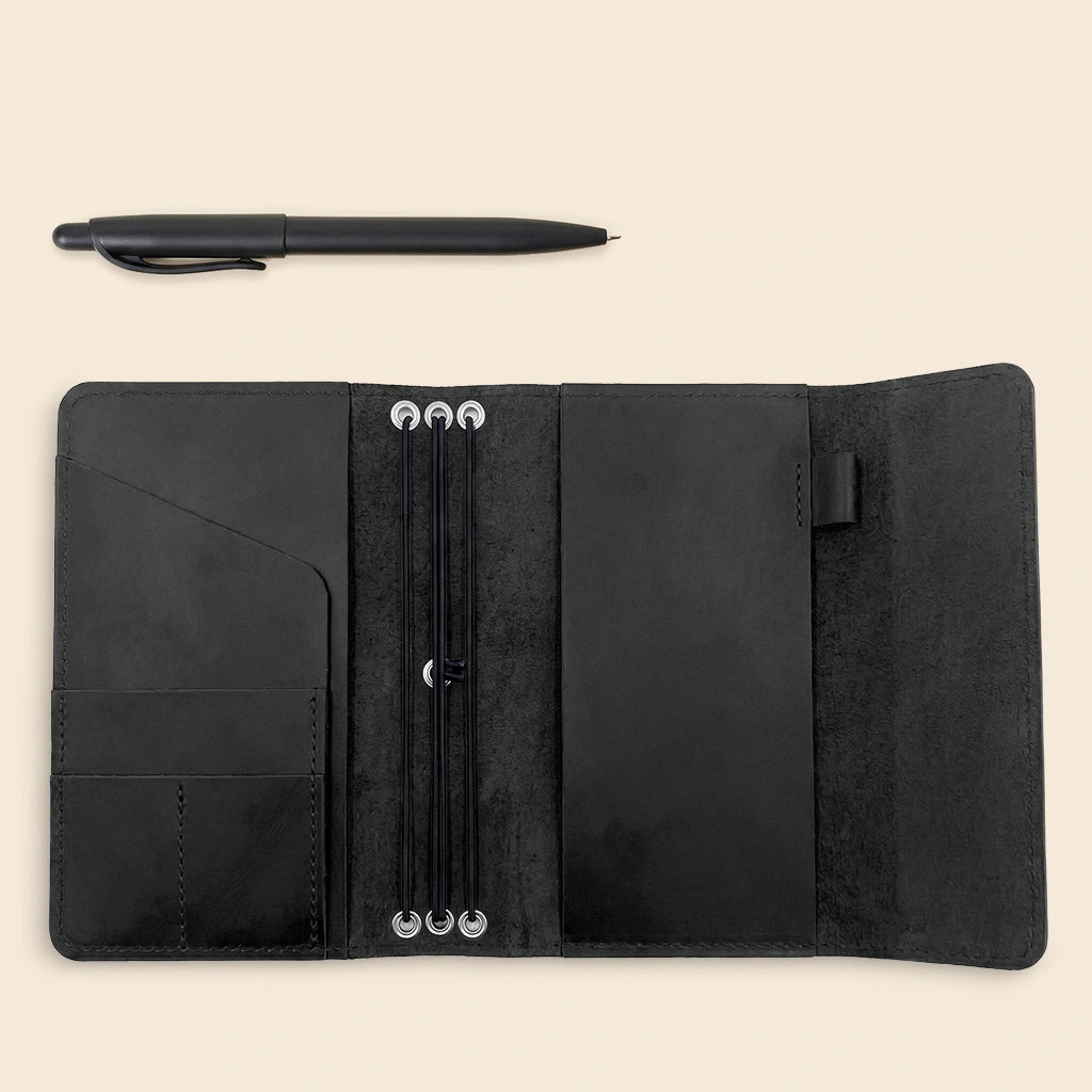 Handmade leather notebook cover with refillable elastic bands and storage compartments inside.