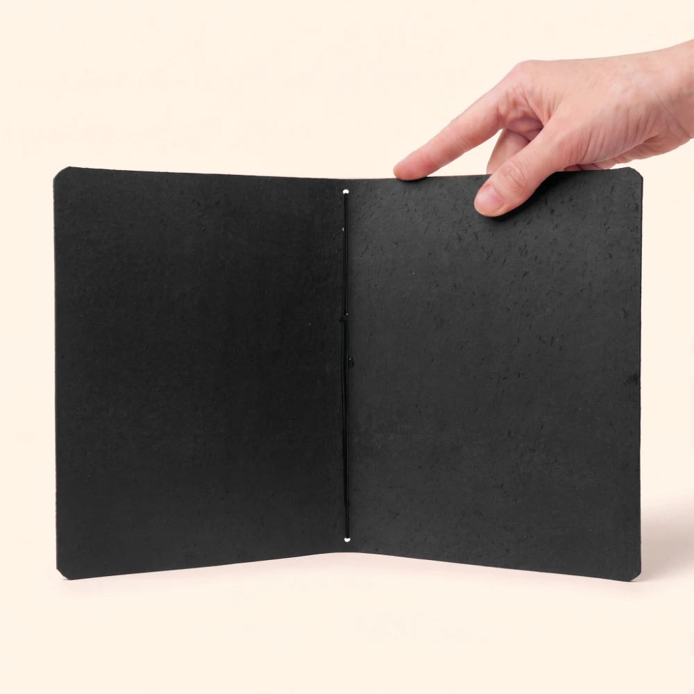 Minimalist genuine leather journal cover holding a plain notebook with flexible elastic.