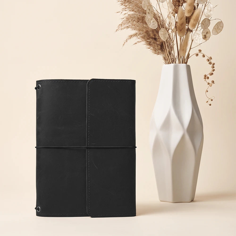 Refillable leather planner cover featuring handcrafted construction and three elastic notebook holders.