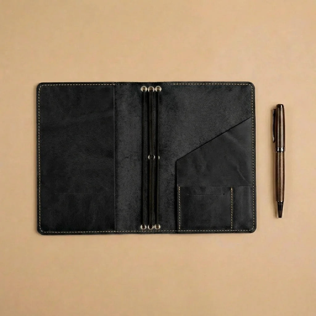 Black leather journal held open by a hand on a beige background