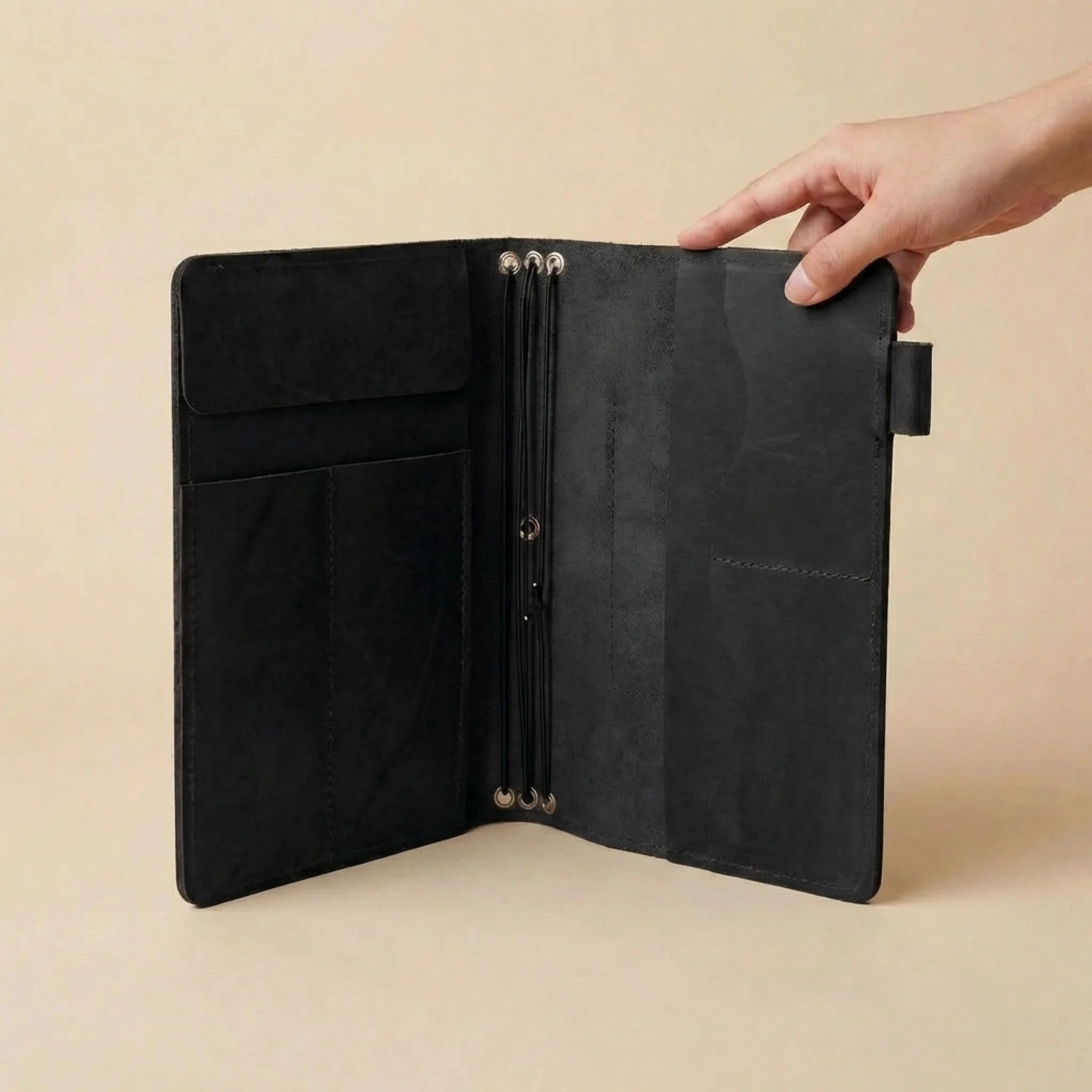 Black leather notebook and pen on a beige background