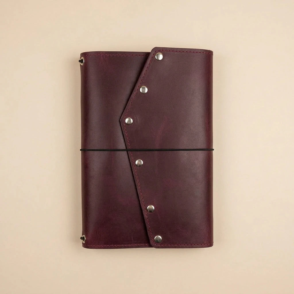 Brown leather notebook with metal rivets on a beige background