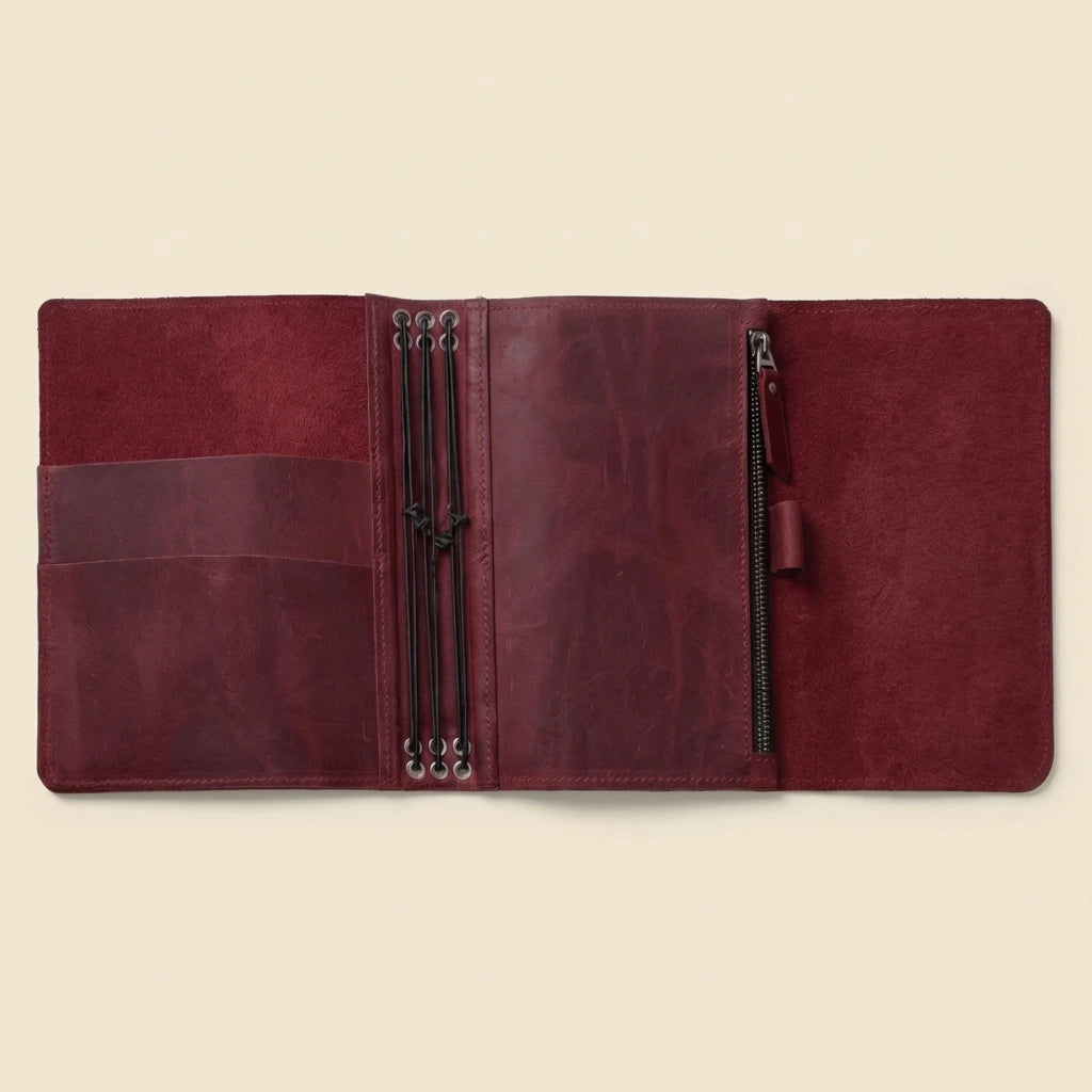 Brown leather journal with zippers on a beige background