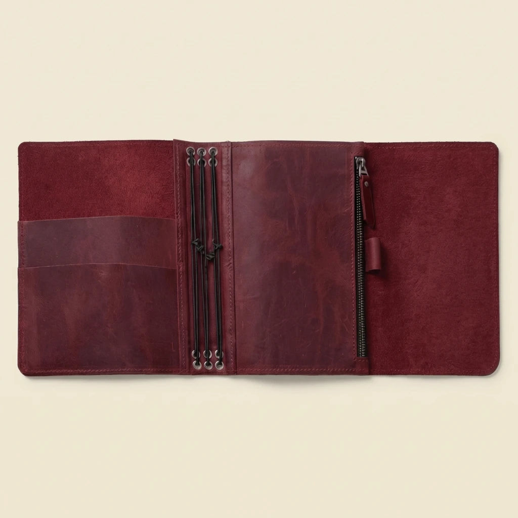 Brown leather journal with zippers on a beige background