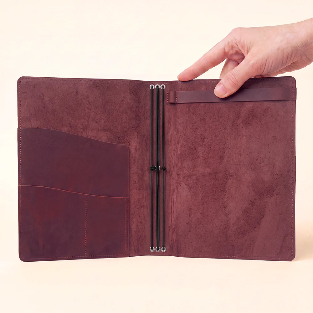 Handmade leather journal case with elastic loops, interior pockets, and sketchbook attachment.