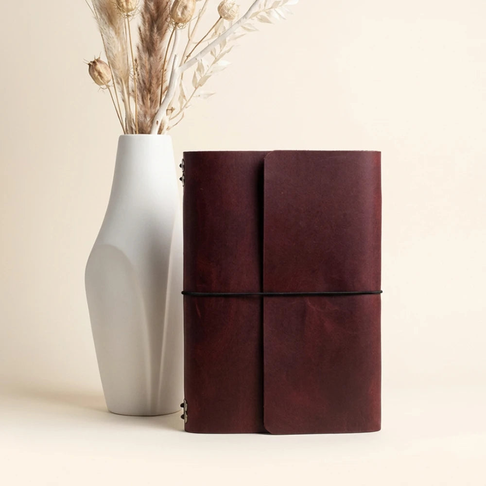 Leather notebook cover offering six flexible insert positions and an attached pen loop.