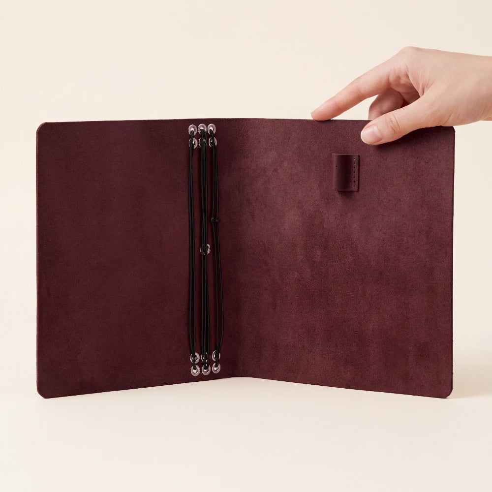 Stylish leather planner cover supporting six notebooks with flexible elastic bands.
