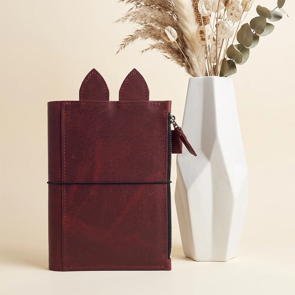 Refillable planner organizer featuring a roomy zippered pocket and whimsical leather ears.