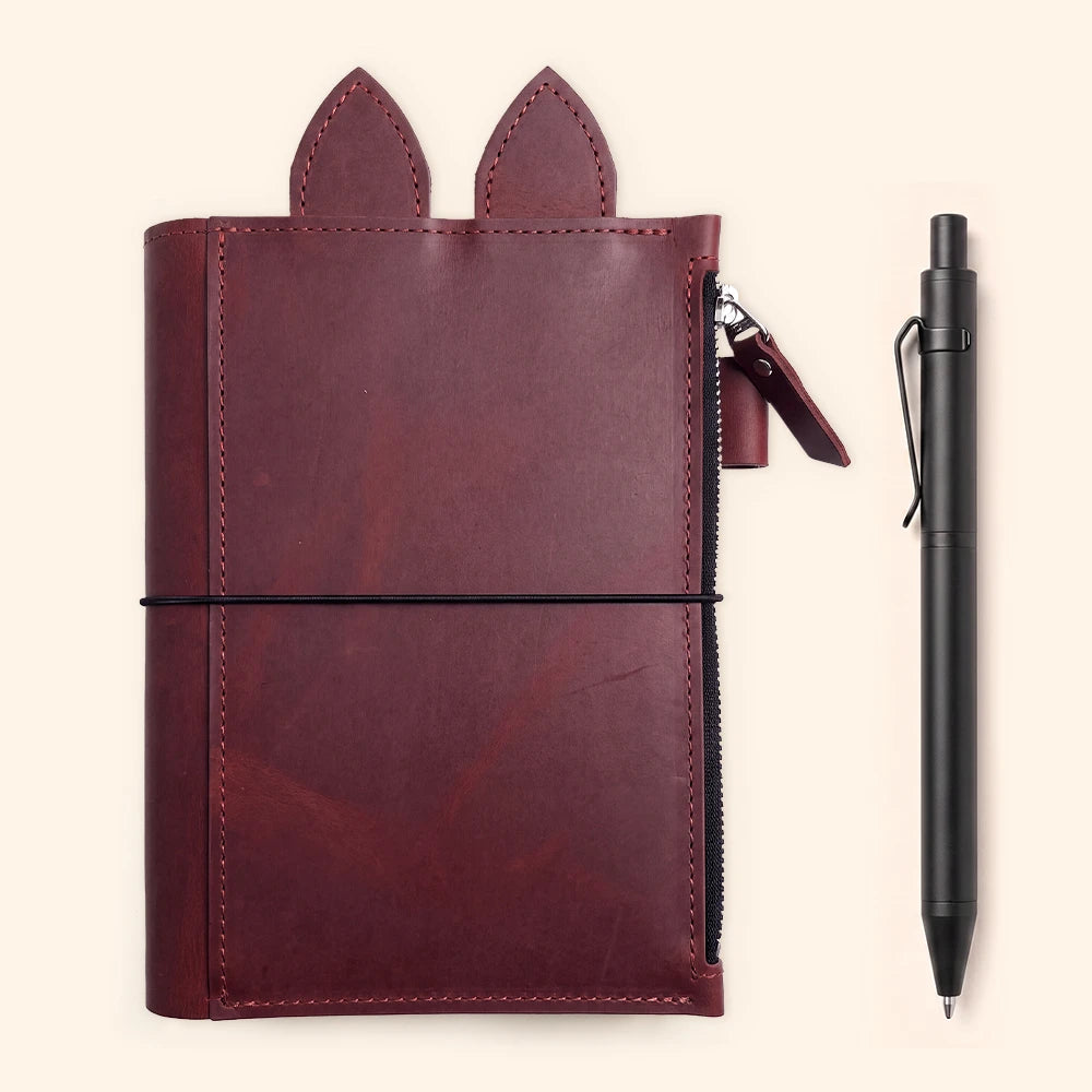 Refillable leather notebook organizer featuring zipper compartment, pen loop, decorative ears, and three elastics.