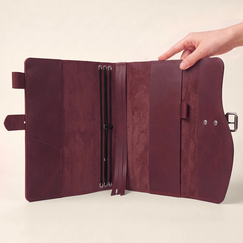 Natural leather notebook organizer displaying storage sections, pen loop, integrated bookmark, and comfortable carrying grip.