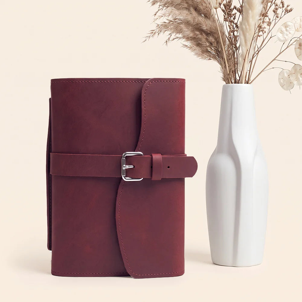 Genuine leather writing case displaying practical pockets, pen loop, bookmark ribbon, and carrying handle.