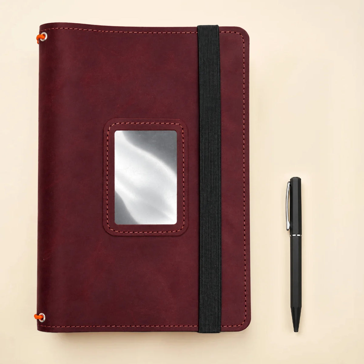 Handmade leather notebook cover showing three elastic holders and neatly arranged accessory pockets.