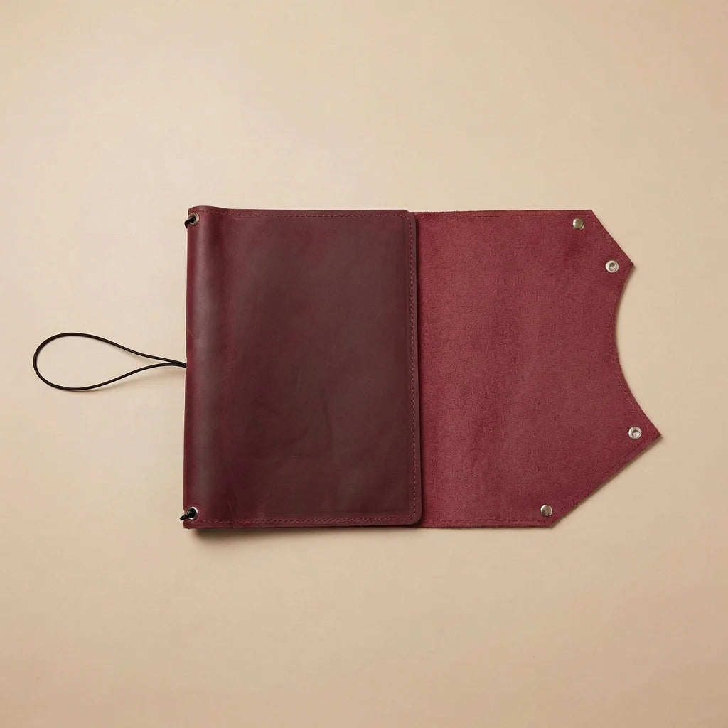 Brown leather journal cover with strap on a beige background