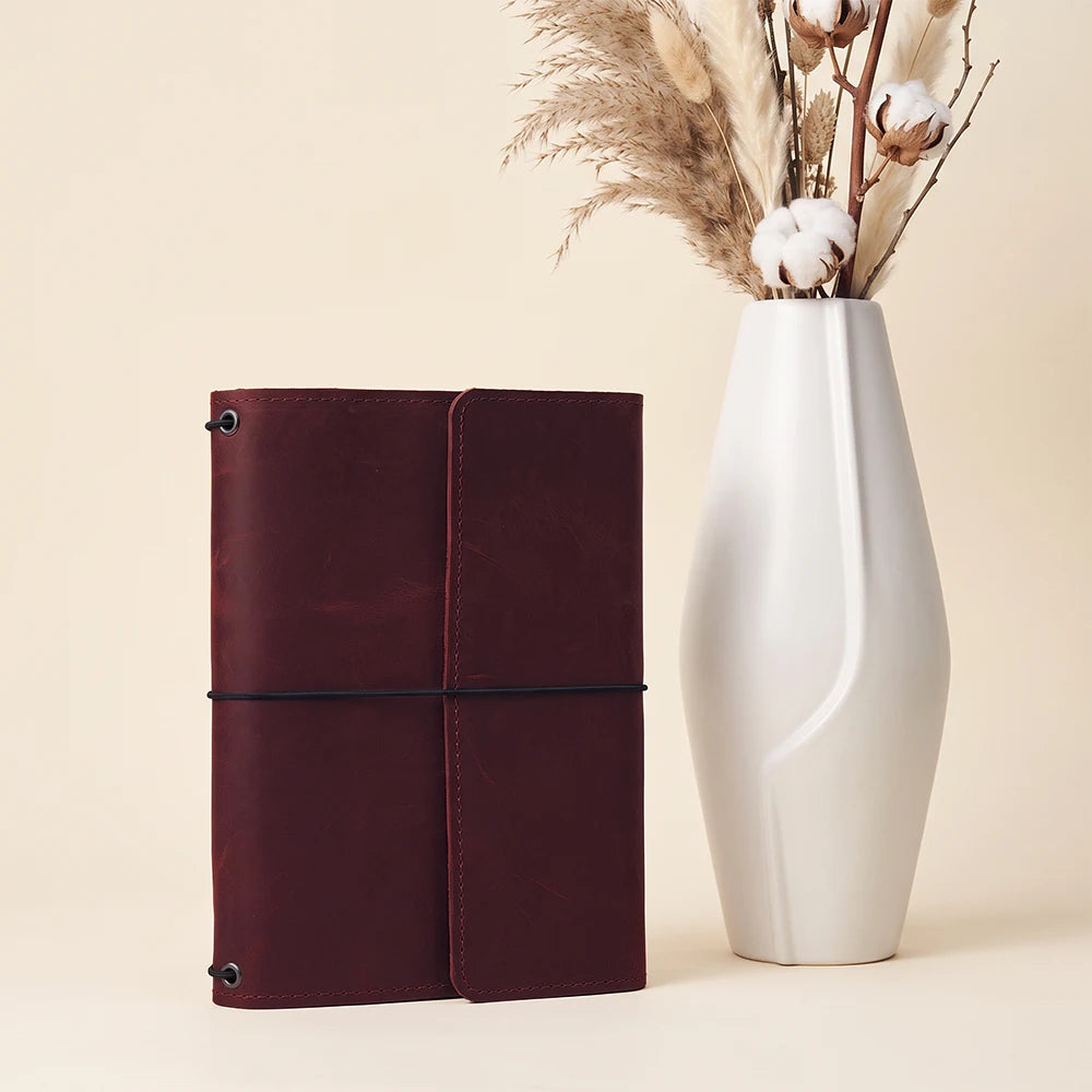 Leather notebook holder offering three elastic straps and convenient pockets for everyday essentials.