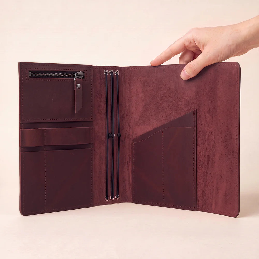 Genuine hide notebook organizer designed with useful compartments and convenient writing instrument storage.