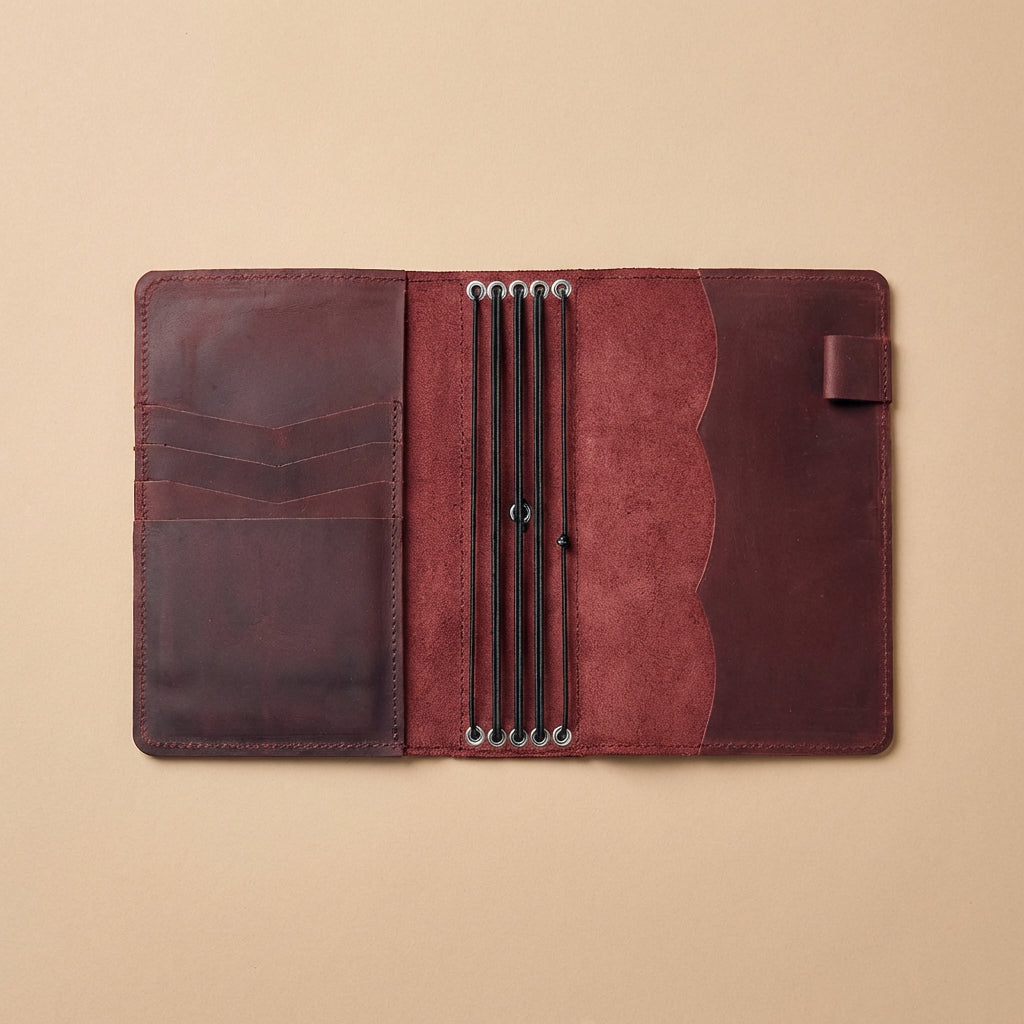 Brown leather journal cover with pen holder on a beige background