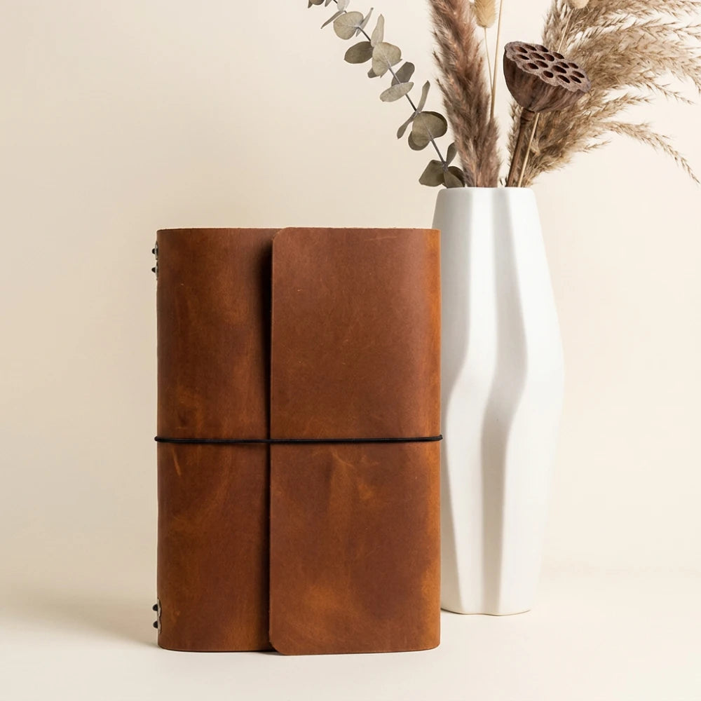 Premium leather notebook organizer combining modular inserts with a convenient pen loop.