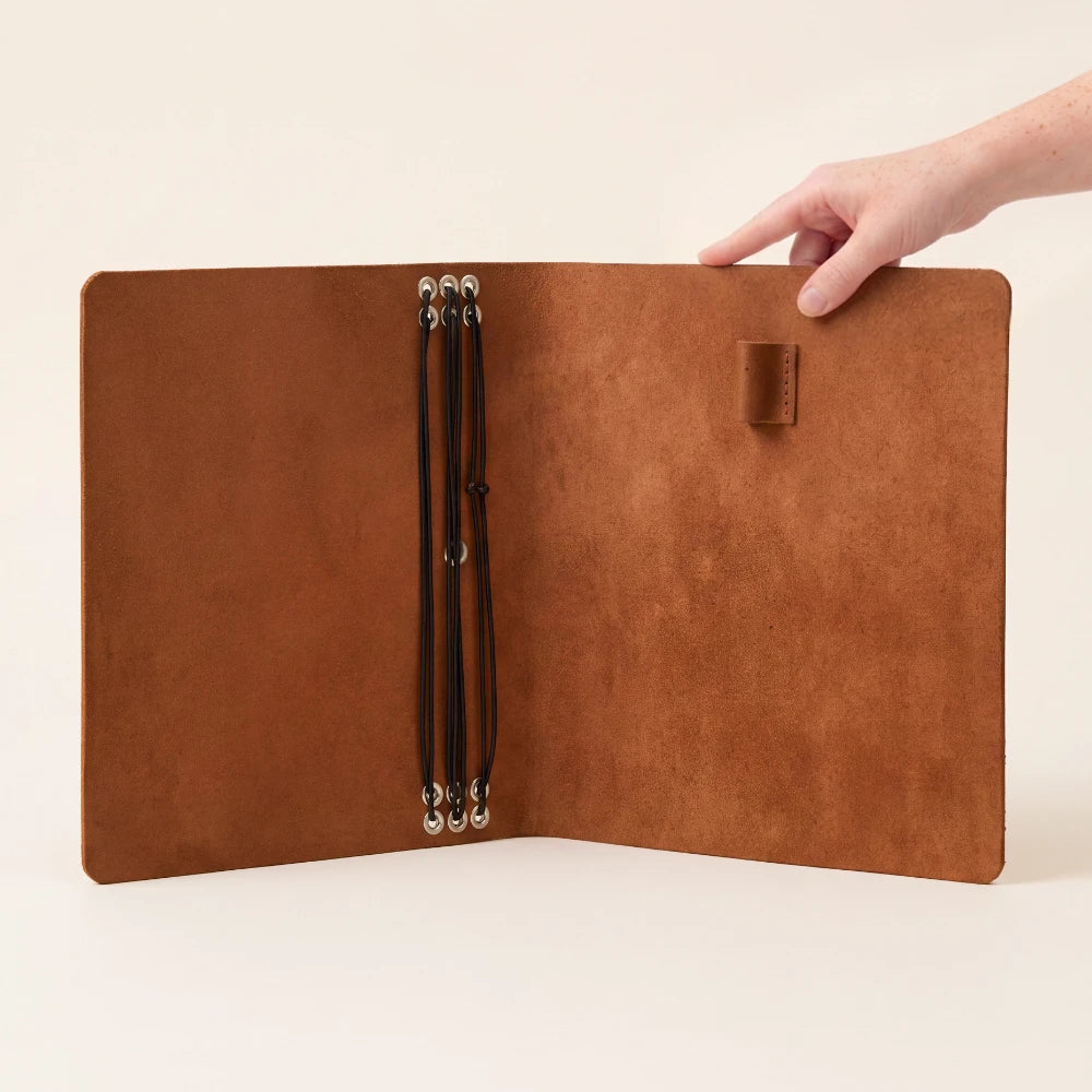 Reusable leather cover with six flexible cords for organizing personalized writing refills.