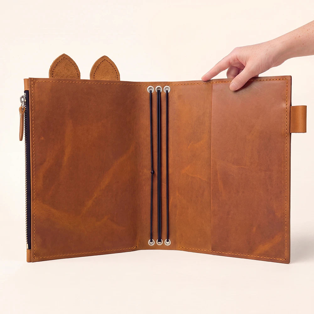 Genuine leather journal organizer opened flat to reveal three flexible elastic insert bands.