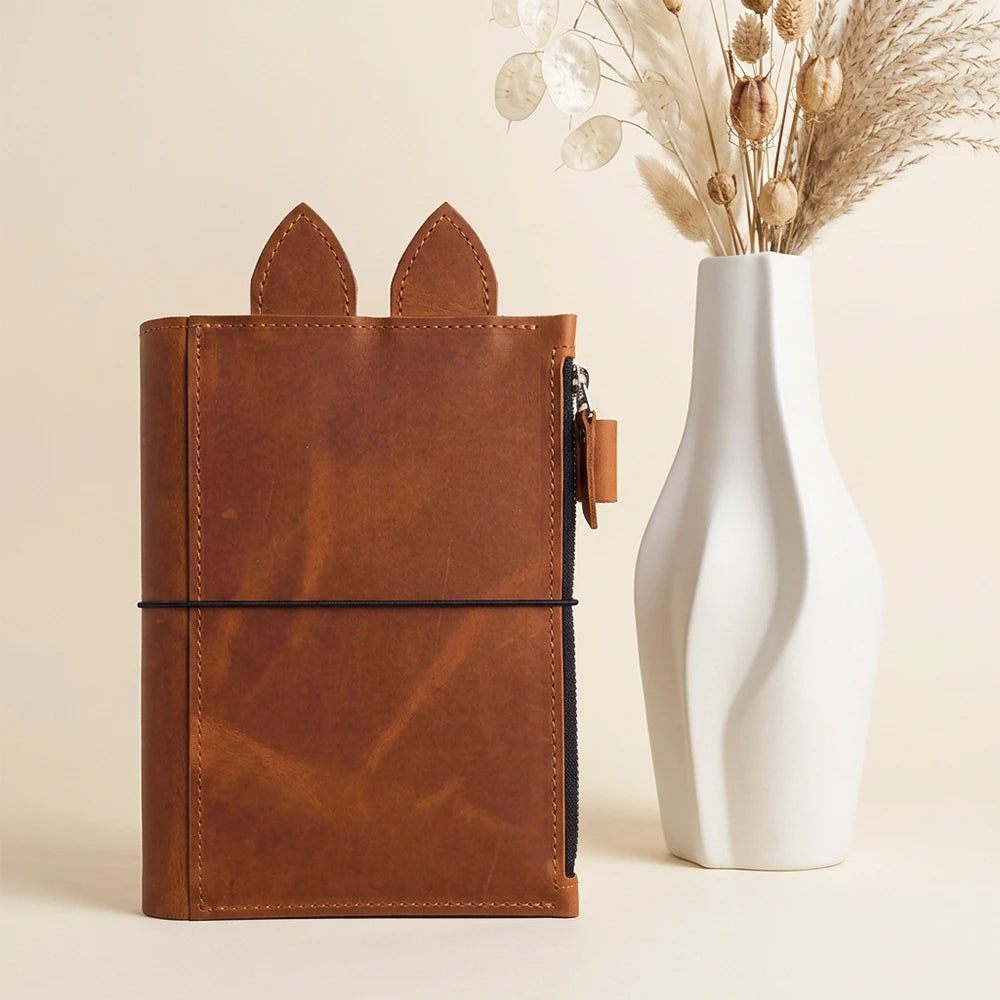 Leather journal organizer designed with a pen loop, zipper pocket, and elastic holders.
