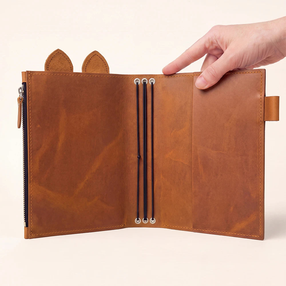 Rustic leather notebook organizer featuring large zipper pocket, pen holder, decorative ears, and three bands.