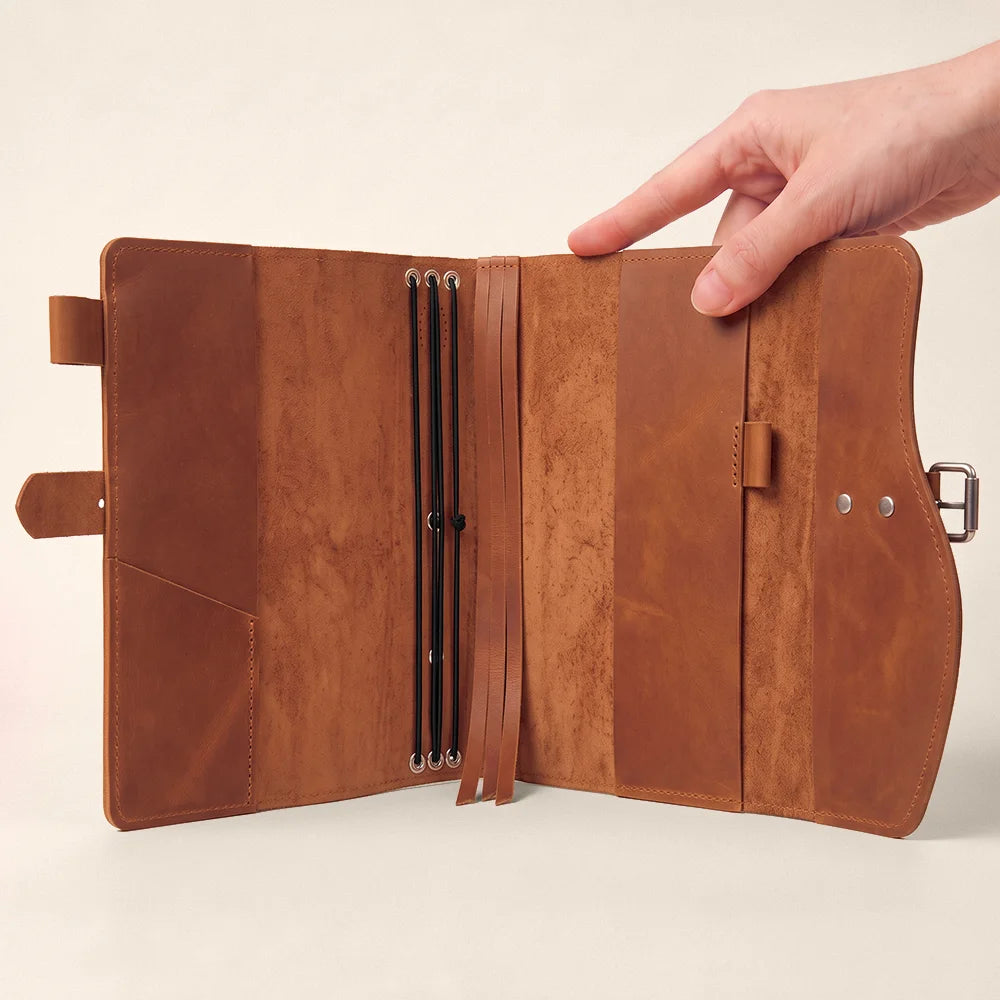 Natural leather journal cover designed with storage pockets, pen holder, integrated bookmark, and convenient carry handle.