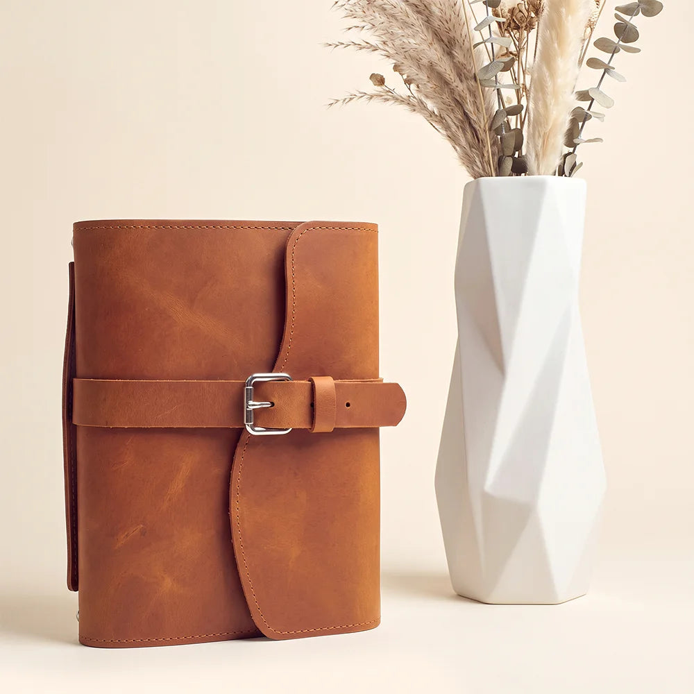 Leather journal case designed with practical interior pockets, secure pen loop, bookmark, and comfortable carrying handle.