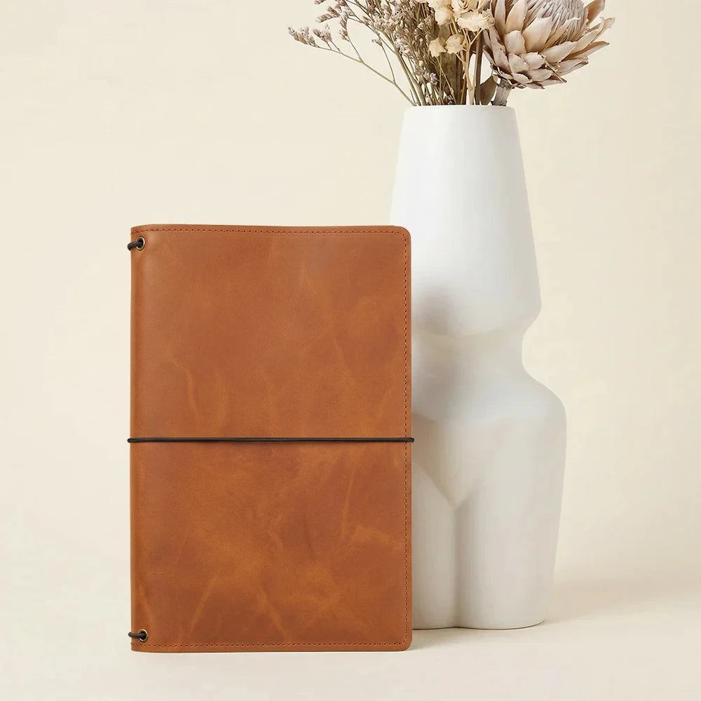 Leather notebook protector featuring organized interior storage and three elastic notebook straps.