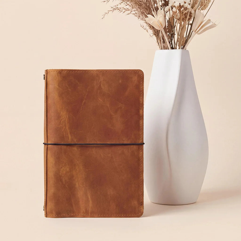 Leather travel journal cover with organized storage pockets and flexible elastic notebook system.
