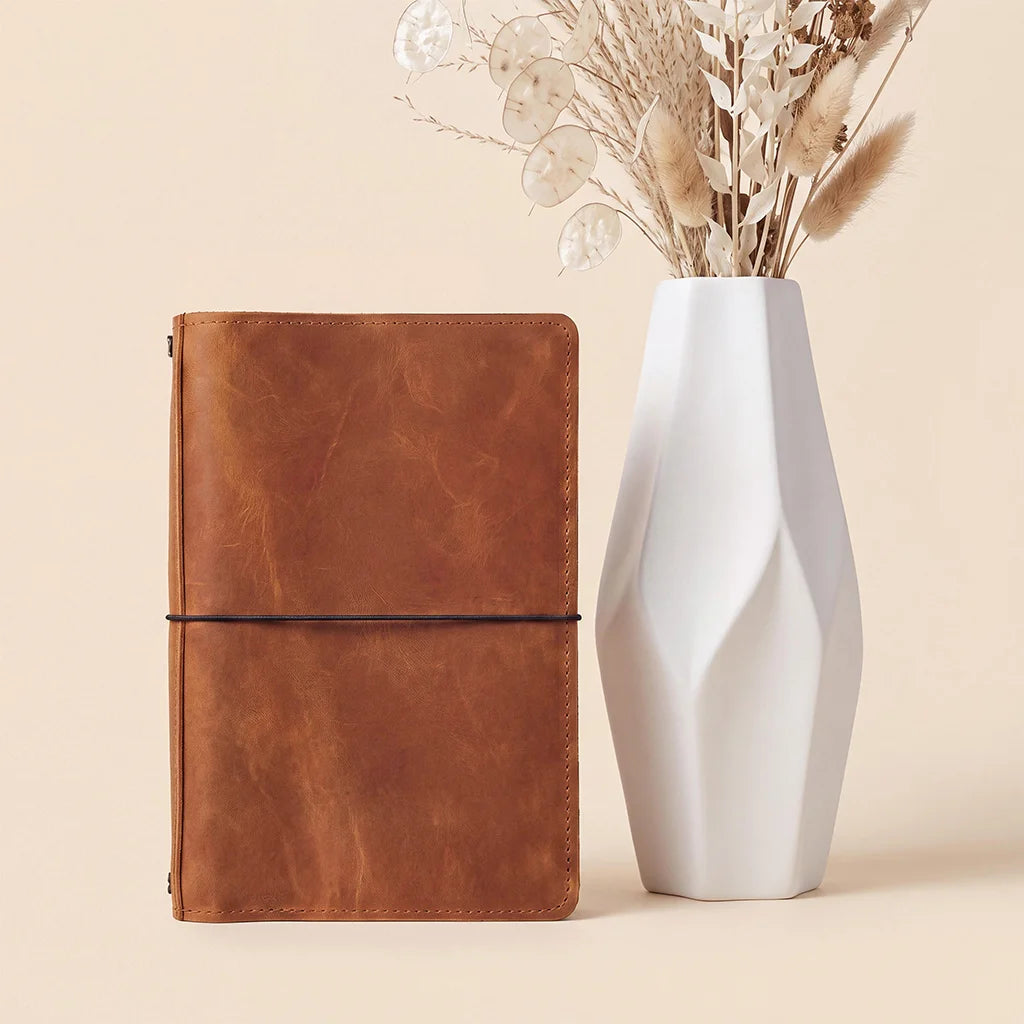 Handmade leather refillable notebook cover featuring durable stitching, pockets, and elastic bands.