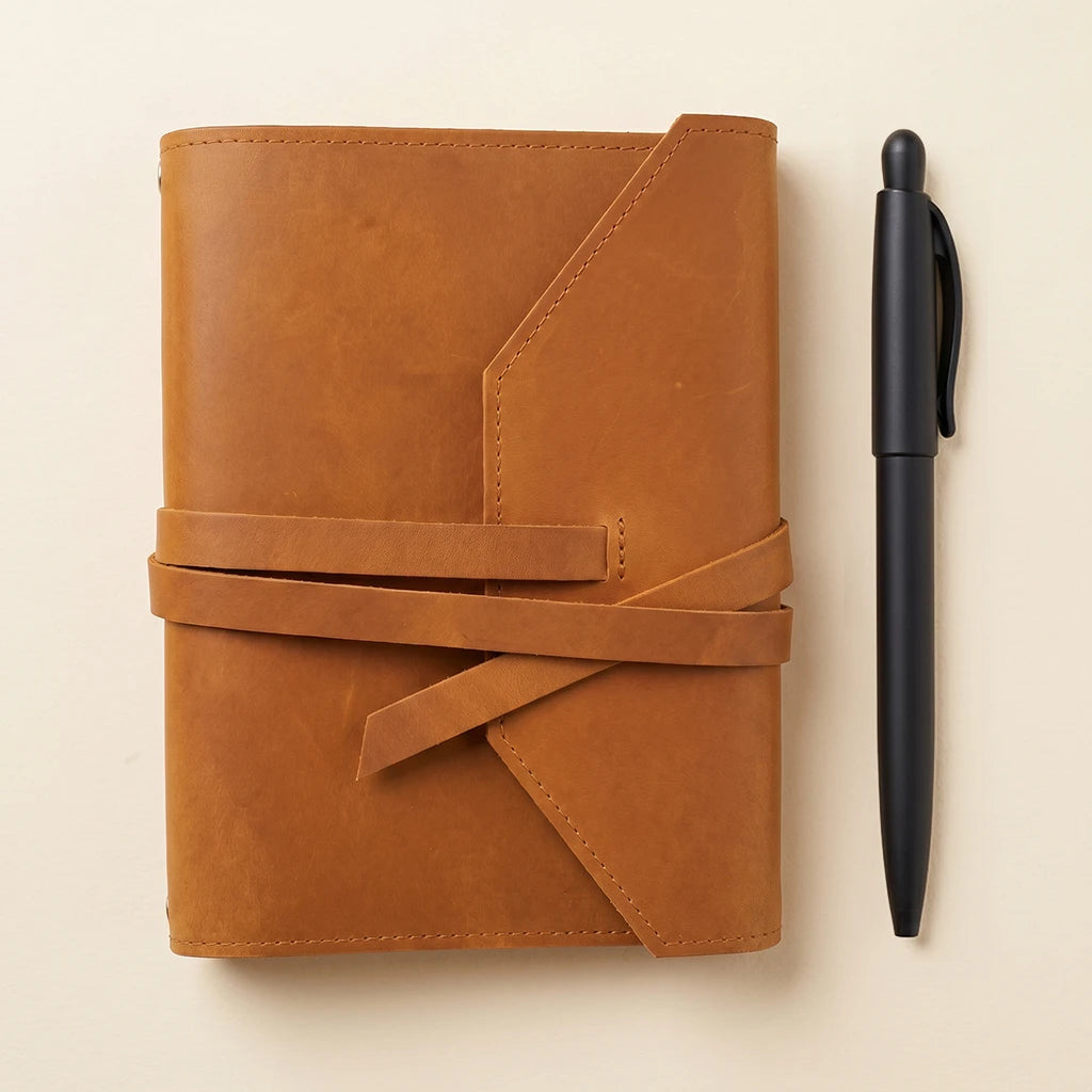 Personalized leather notebook sleeve with elastic closure and pen holder.