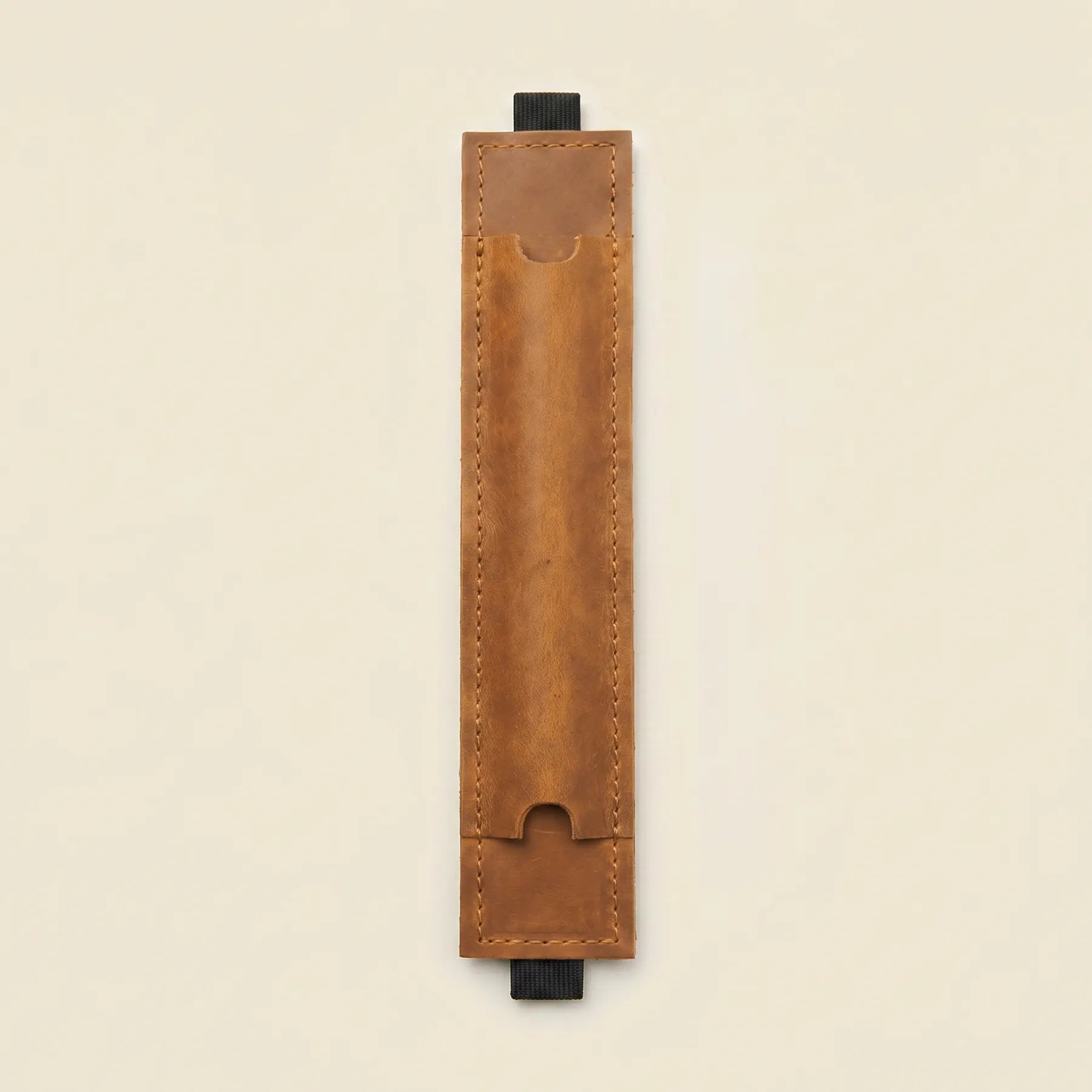 Handmade leather pen holder for planners offering secure elastic notebook attachment system.