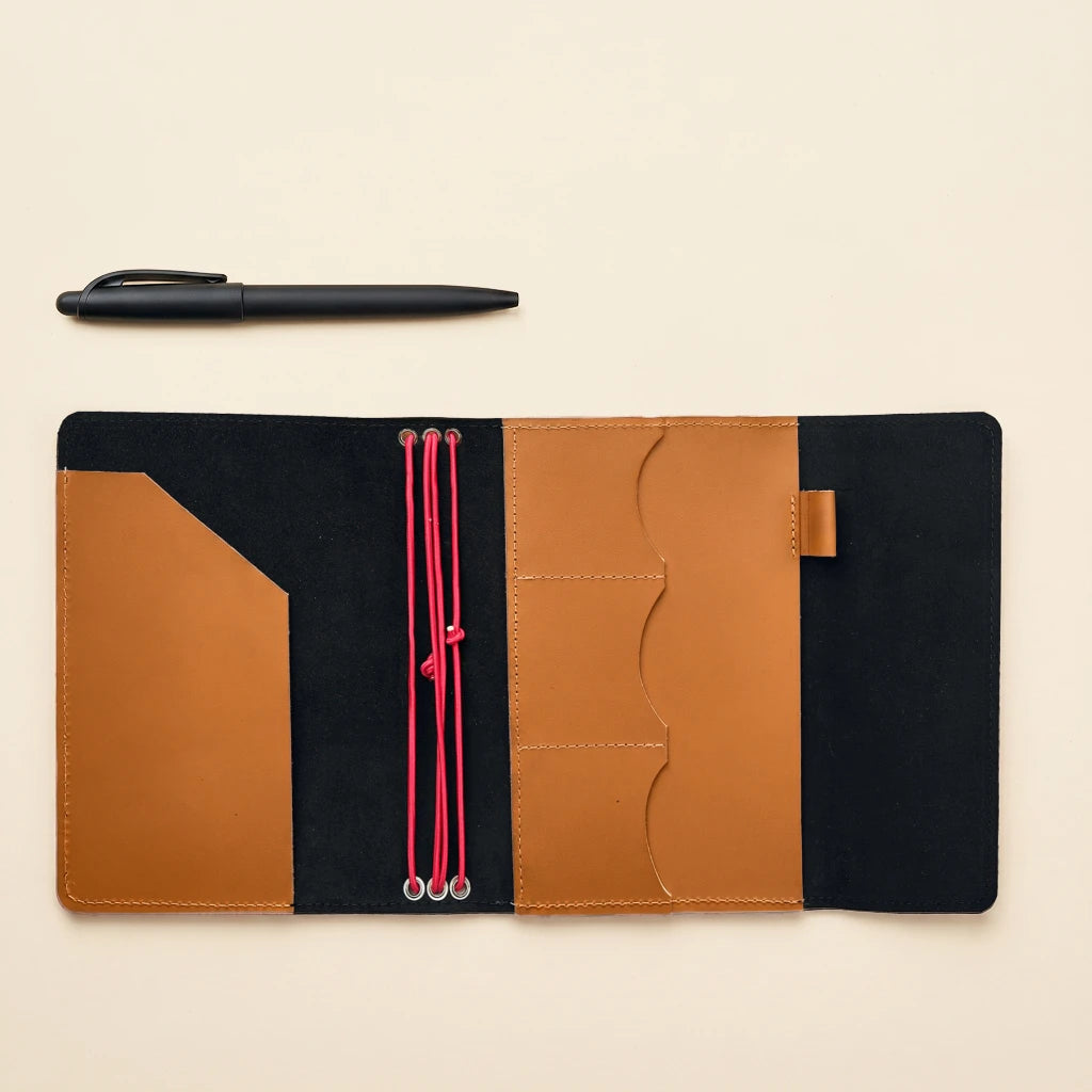 Refillable leather journal cover with elastic straps, pockets, and attached pen holder