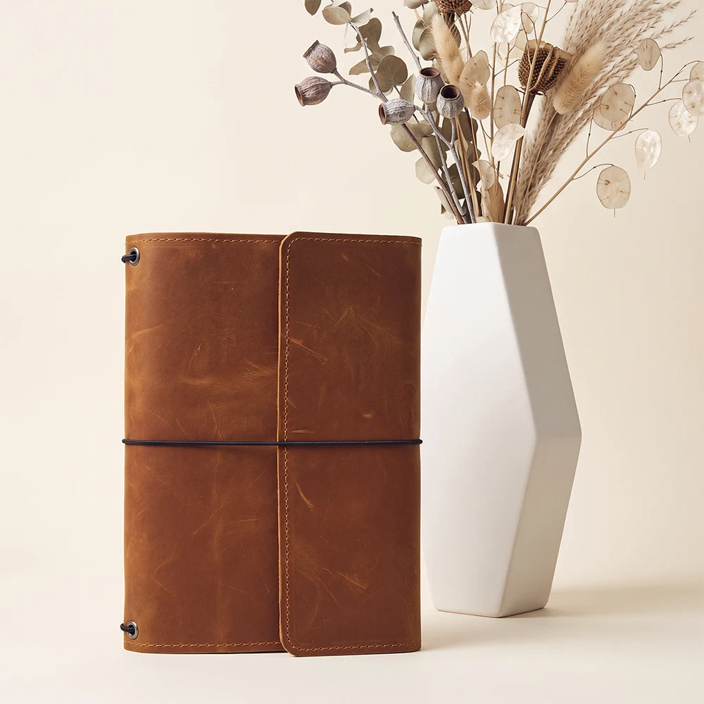 Handmade leather notebook case featuring three elastic bands and organized interior pocket layout.