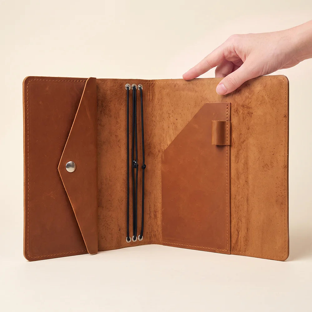Premium leather journal holder with elastic notebook inserts and practical accessory storage pockets.