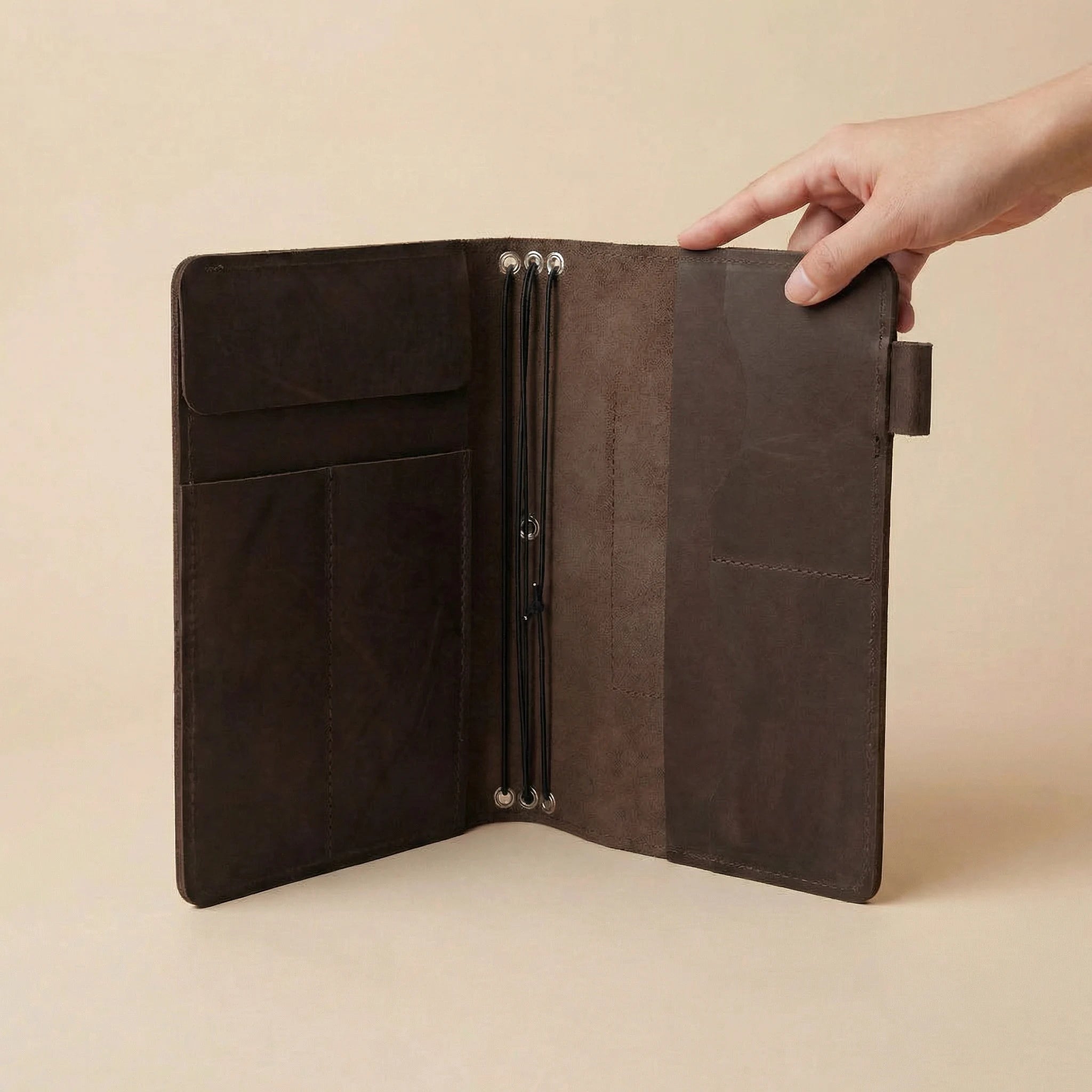 Brown leather journal cover held open by a hand on a beige background