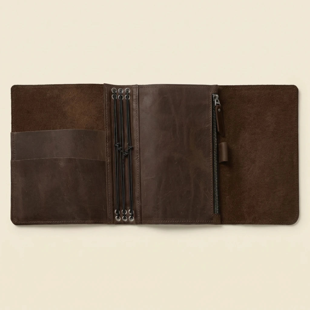 Brown leather journal with zippers on a beige background