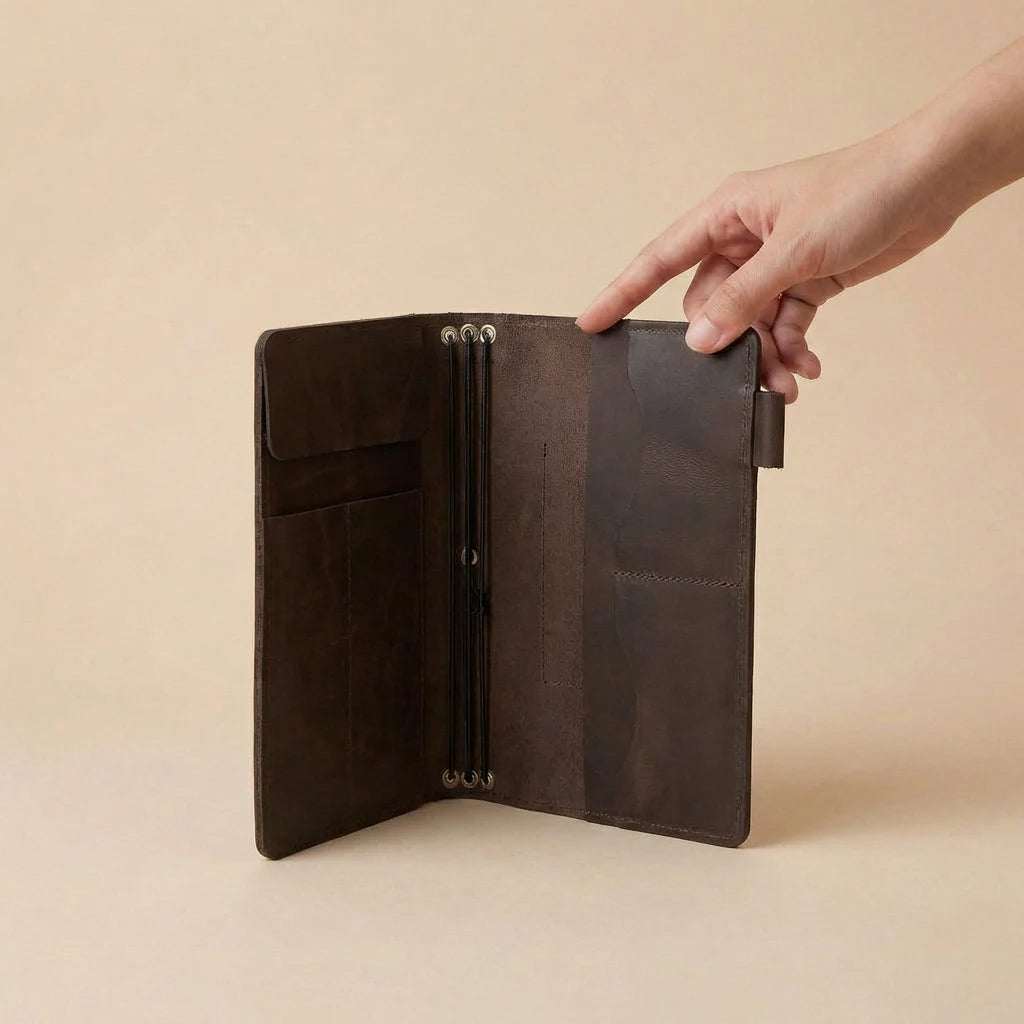 Brown leather journal cover held by a hand on a beige background