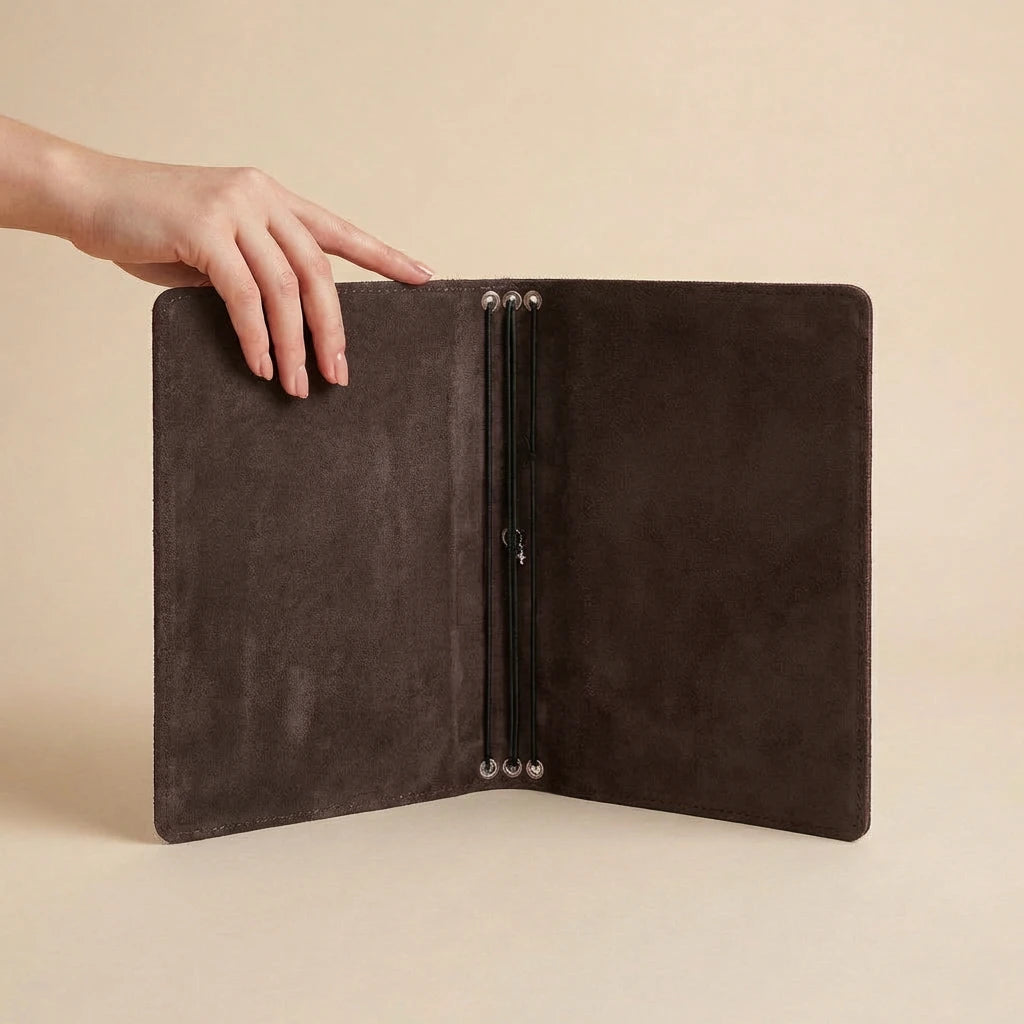 Hand holding open a dark brown leather folder against a beige background
