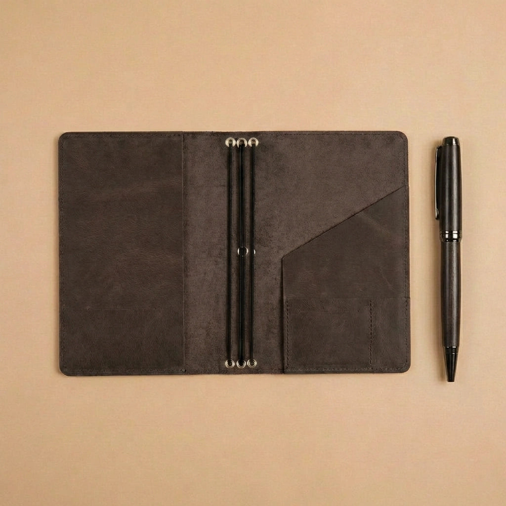Black leather notebook with pen on a beige background