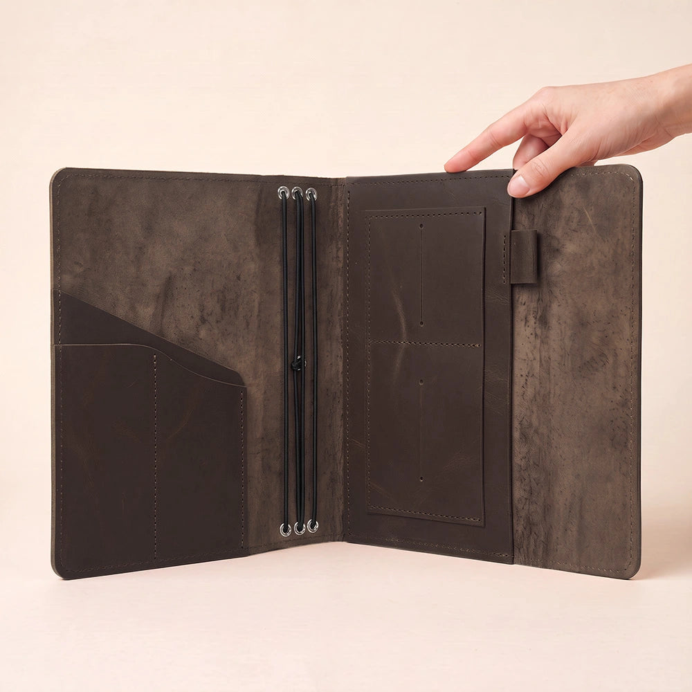 Minimalist leather notebook organizer crafted with interior sleeves and dedicated leather pen strap.