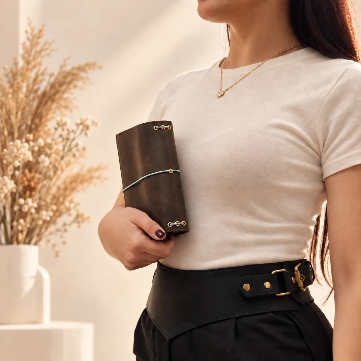 Young woman presenting a handcrafted leather journal cover with a rustic and timeless look.