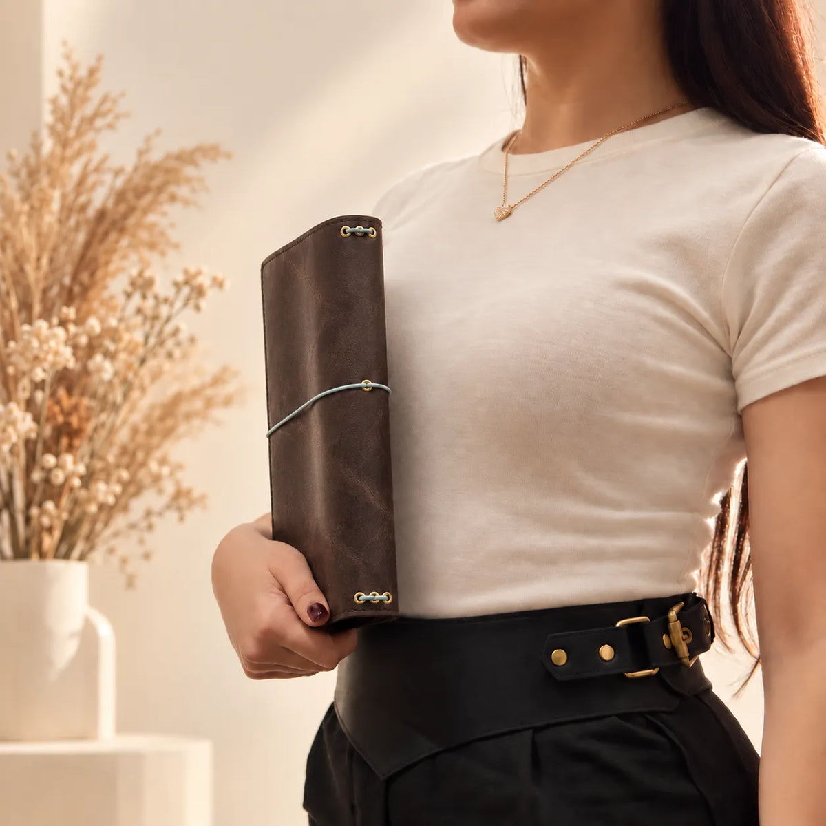 Female hands presenting a genuine leather journal cover with visible natural leather grain.
