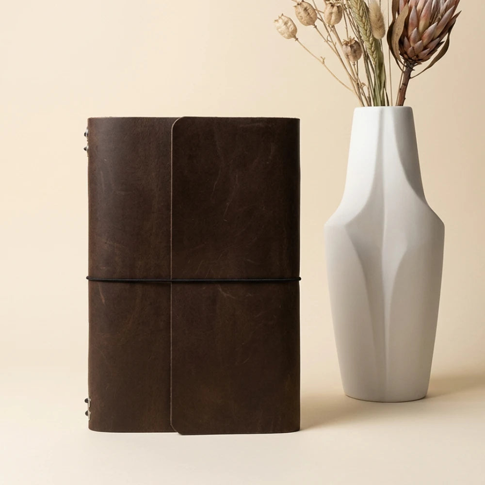 Handmade leather notebook case supporting six inserts through flexible stretch bands.