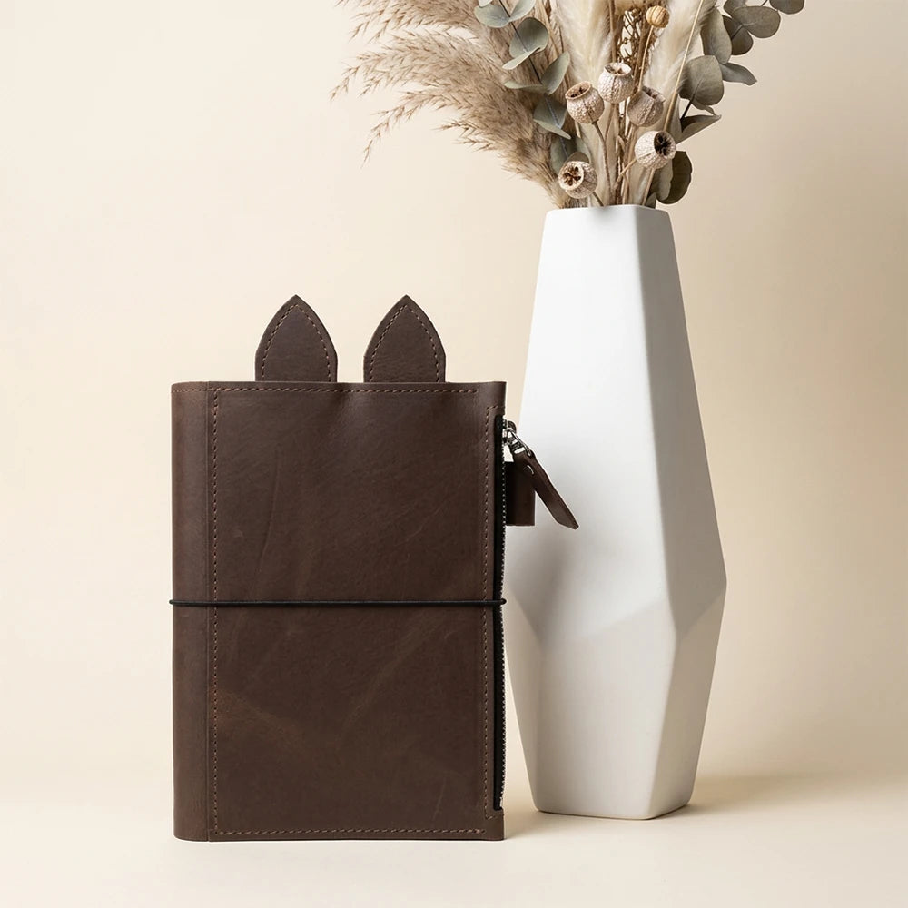 Handmade leather cover with whimsical ears, smooth interior, and practical zipper storage.